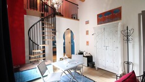 A dining area with a table, chairs, a chandelier, a staircase, and a white cabinet.