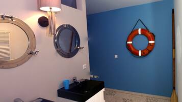 A bathroom with two round mirrors, a sink, and a life preserver hanging on the wall.