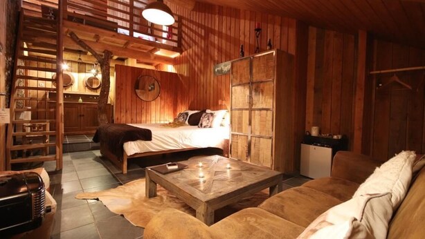 A rustic wooden interior with a bed, sofa, and a coffee table.