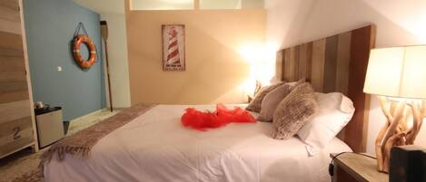 A bedroom with a bed, a nightstand, a lamp, a wall clock, and a framed picture.