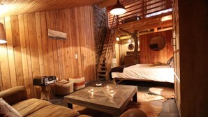 A cozy, wooden-furnished room with a bed, a coffee table, and a sofa.