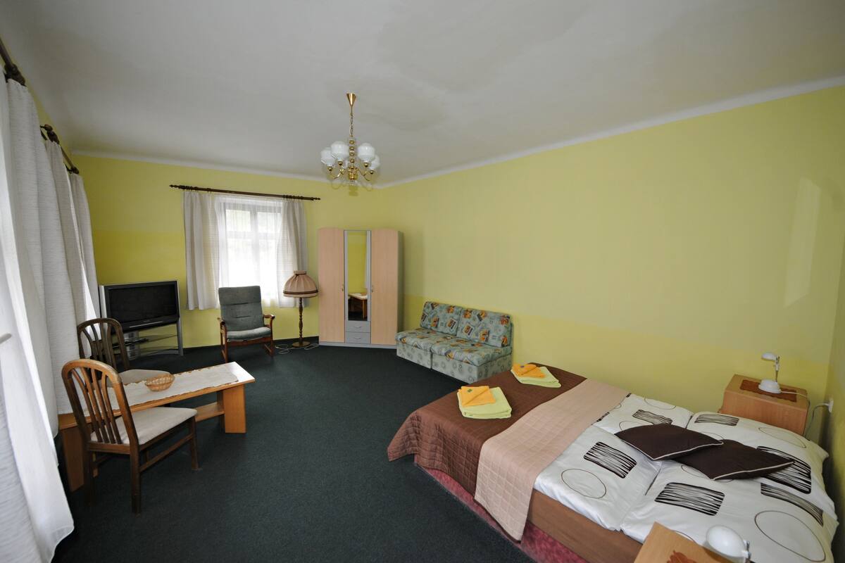A hotel room with a bed, a desk, a chair, a television, and a sofa.