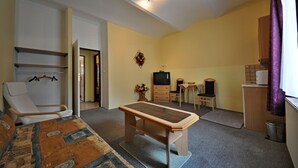 Una habitación pequeña con cama, una mesita, televisión y una silla.