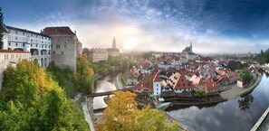 Une vue panoramique d’une ville historique, avec une rivière, un pont et un imposant beffroi.