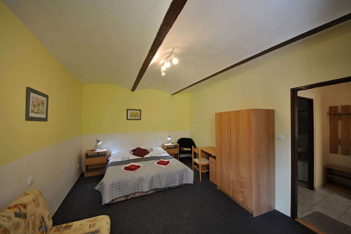 A bedroom with a bed, bedside tables, a chair, a wardrobe, and a door leading to a bathroom.