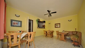 Comedor con mobiliario de madera, ventilador de techo y paredes amarillas.