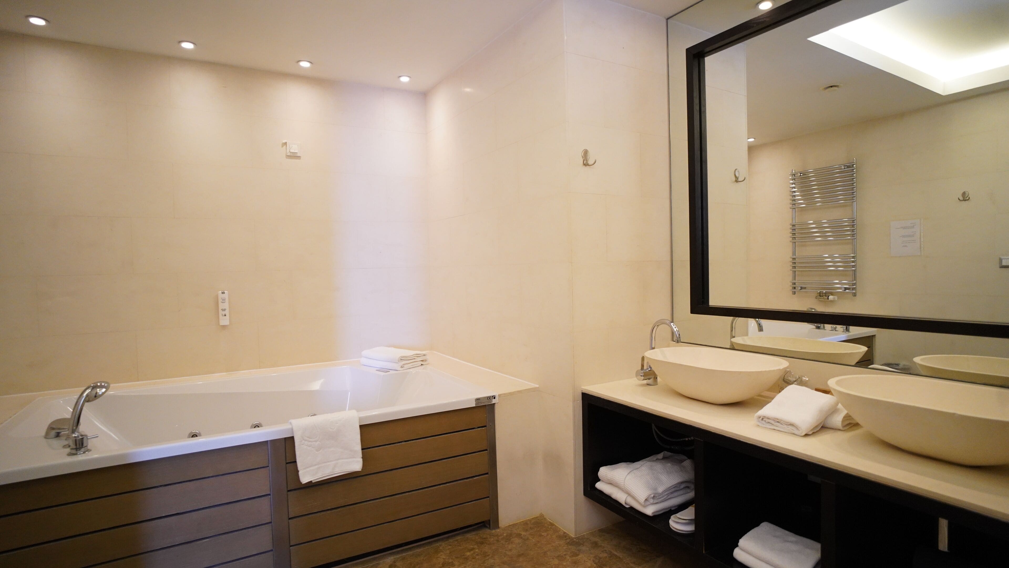 Un baño moderno con bañera, dos lavamanos y un espejo grande.