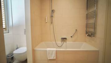 Un baño con bañera, inodoro y ducha.