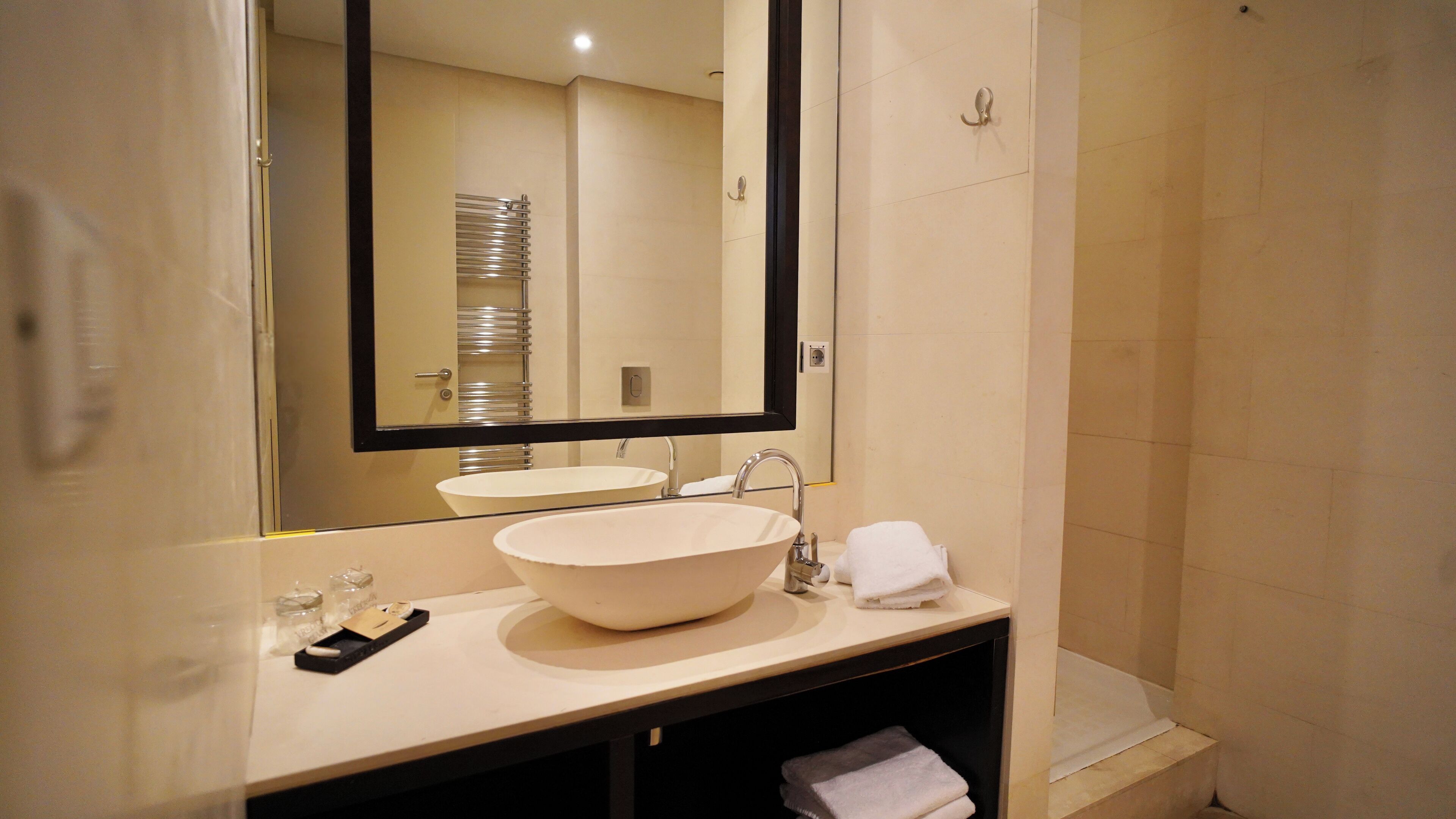 A bathroom with a large sink, a mirror, and a towel rack.
