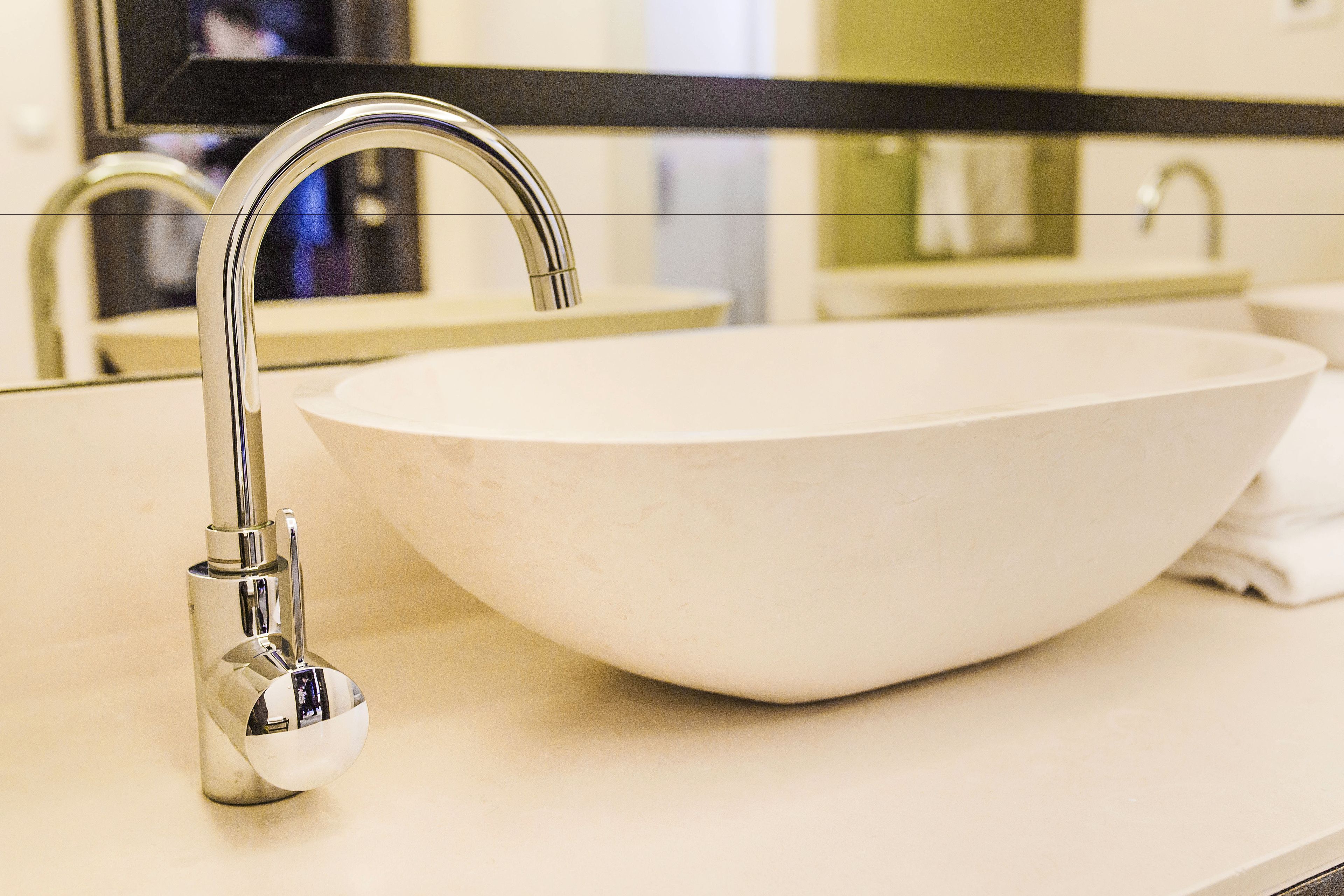 Un baño moderno con un lavamanos blanco, grifo cromado y un espejo grande sobre el lavamanos.