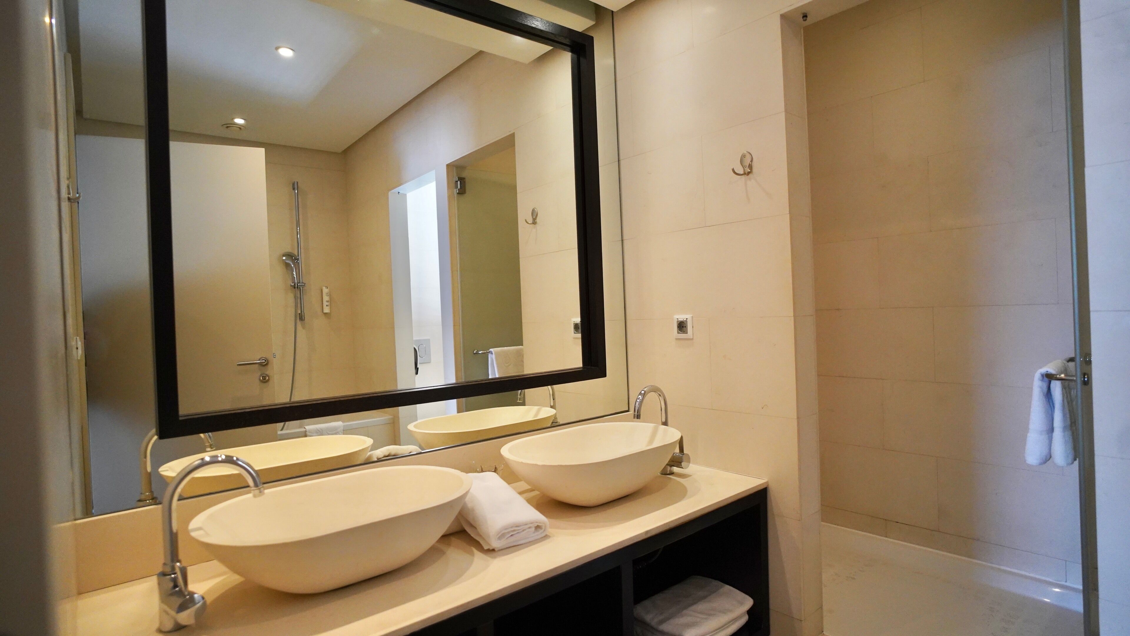 Un baño moderno con dos lavamanos, un espejo grande y zona de ducha.