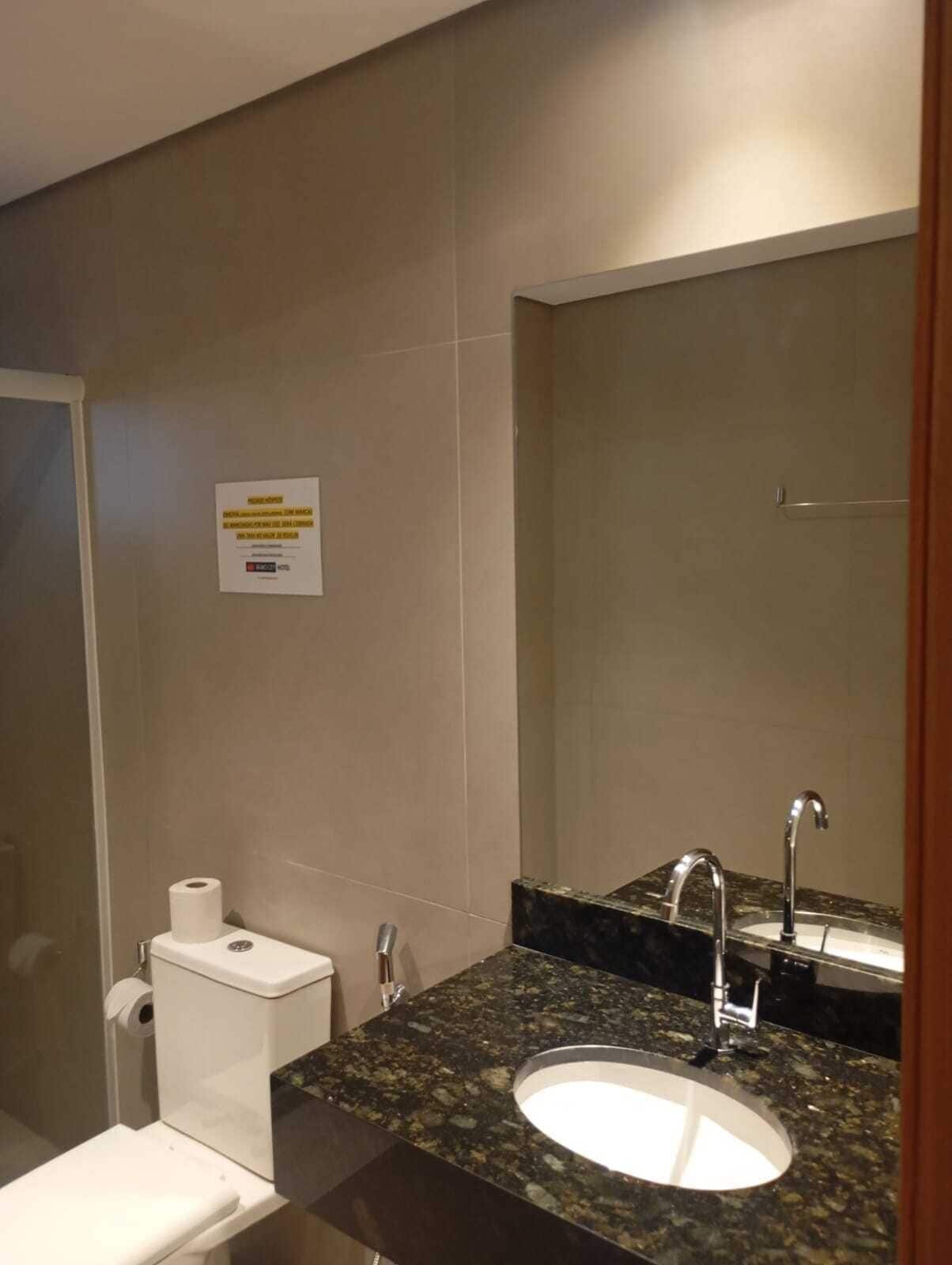 Un baño con inodoro, lavamanos y espejo.