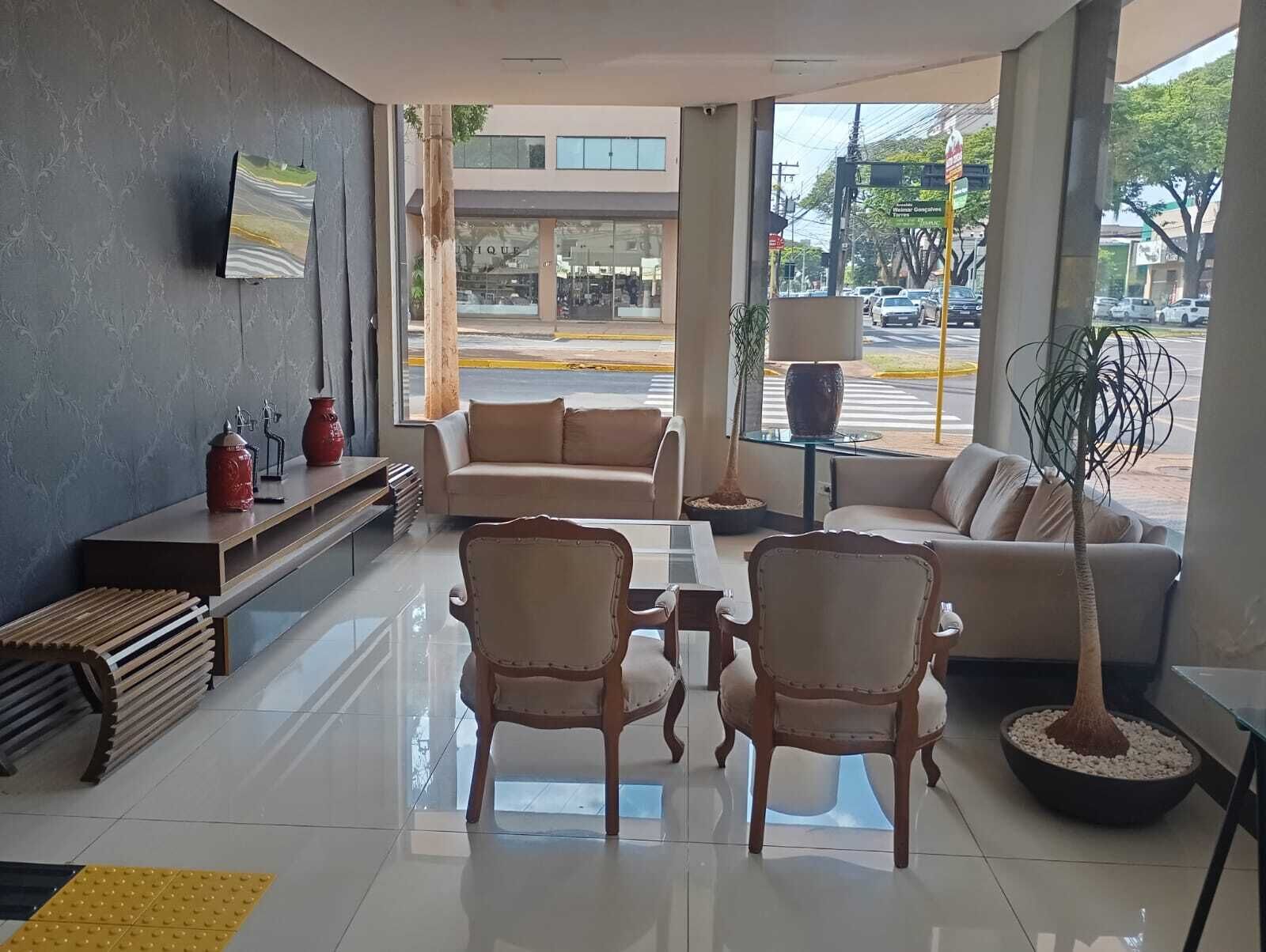 Un hall moderno con un sofá, sillas, una mesa de centro y un televisor montado en la pared.