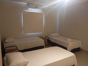 A room with two single beds, a chair, a window, and an air conditioning unit. - Bravo City Hotel Dourados (Dourados)