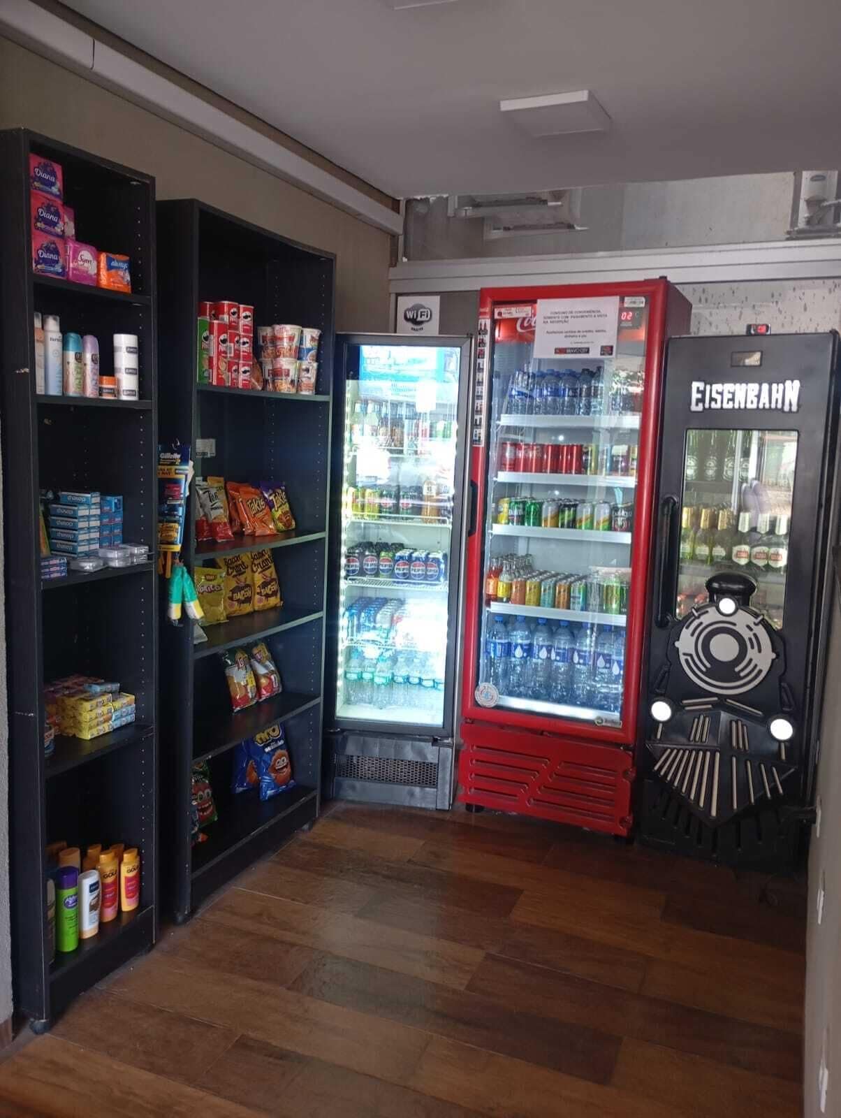 Un espace de vente proposant des collations et des boissons, notamment un réfrigérateur à Coca-Cola et un distributeur automatique de la marque Eisenschmuck.