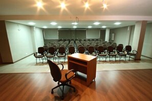 A conference room with rows of chairs, a wooden desk, and a projector screen. - Bravo City Hotel Dourados (Dourados)