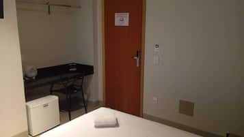 Una habitación pequeña con una cama, un escritorio, una silla y un refrigerador.