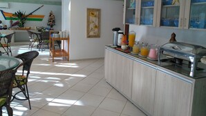 A bright kitchen with a breakfast bar, a dining area with wicker chairs, and a Christmas tree. - Brava Apart Hotel (Florianópolis)