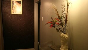 A hallway with a dark textured wall, a framed picture, and a vase with dried plants on a granite countertop.