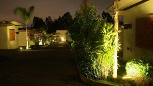 A nighttime view of a hotel entrance with a paved pathway leading to the main building.