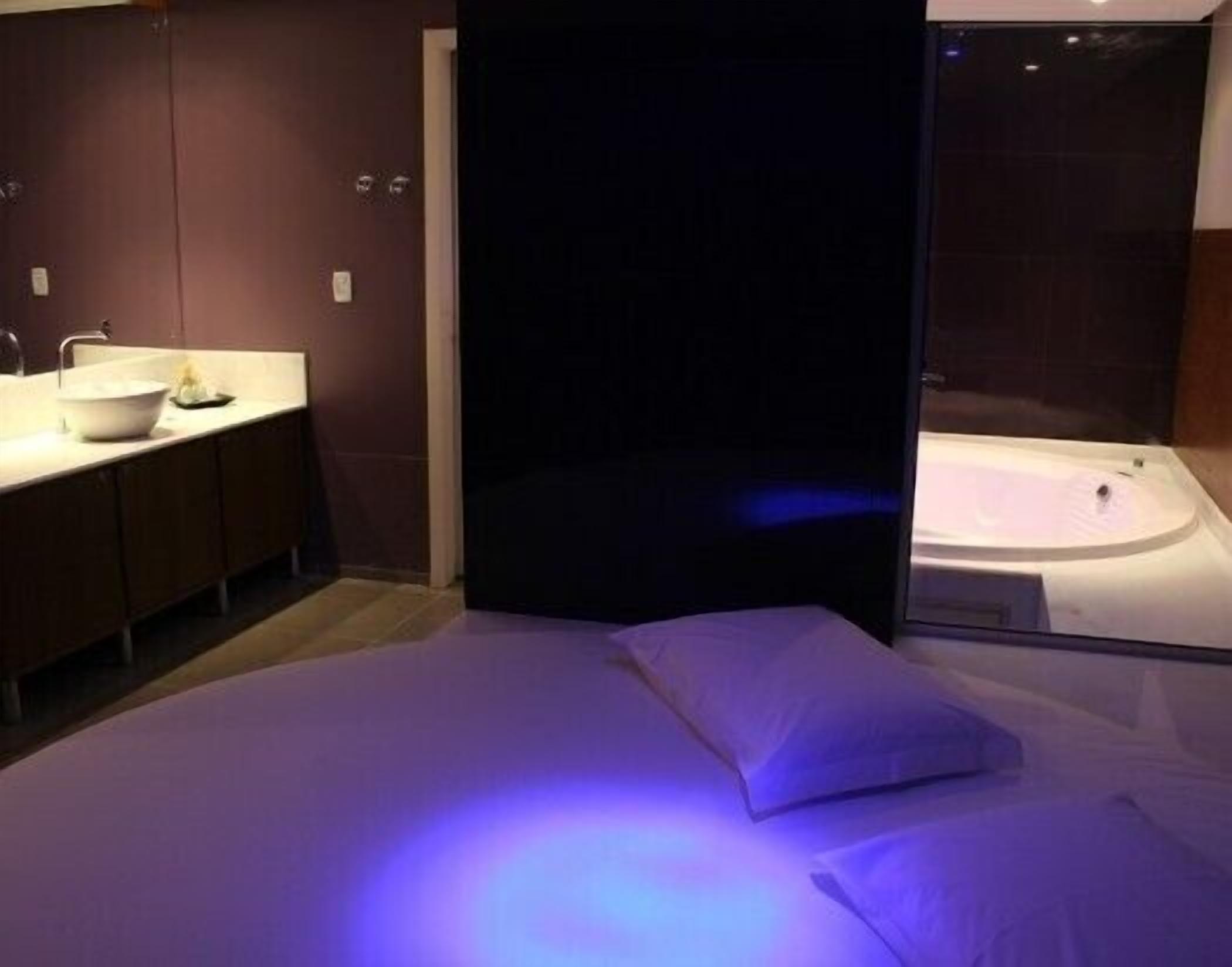 Una habitación de hotel moderna con una cama grande, un baño separado con bañera y un tocador con lavamanos y espejo.