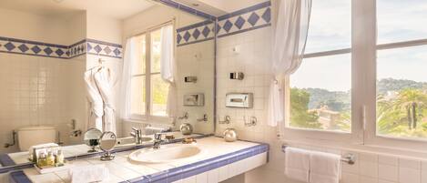 Un baño con dos lavamanos, un espejo grande y una ventana con vistas a follaje.