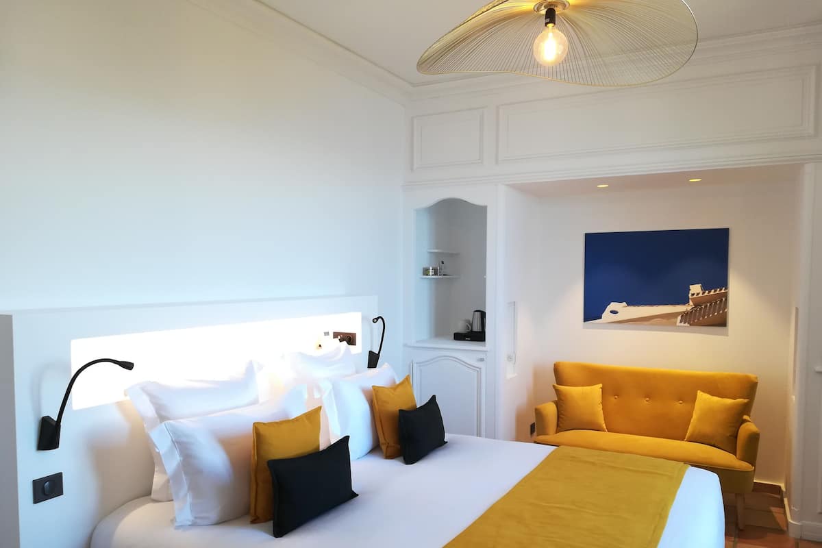 Ein Hotelzimmer mit einem großen Bett, einer Couch, einem Gemälde und einer Deckenleuchte.