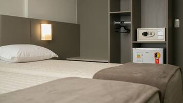 A hotel room with a bed, a bedside table, a wardrobe, and a minibar.
