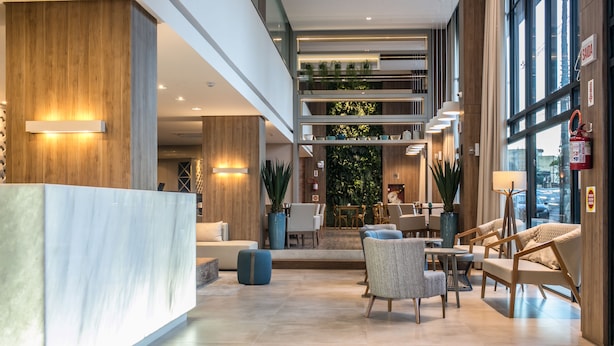 A spacious lobby with a reception desk, seating area, and a view of the interior. - Tri Hotel Premium Criciuma (Criciuma)