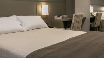 A hotel room with a large bed, a desk, and two chairs.