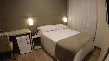 Una habitación de hotel con cama, mesitas de noche, escritorio y una silla.