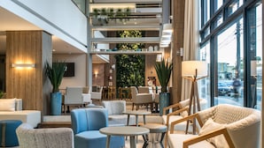 A modern hotel lobby with multiple seating areas, a staircase, and a view of the street through large windows. - Tri Hotel Premium Criciuma (Criciuma)