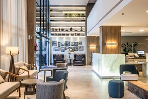 Un lobby moderno con zonas de estar, una recepción y una pared decorada con cuadros y adornos.