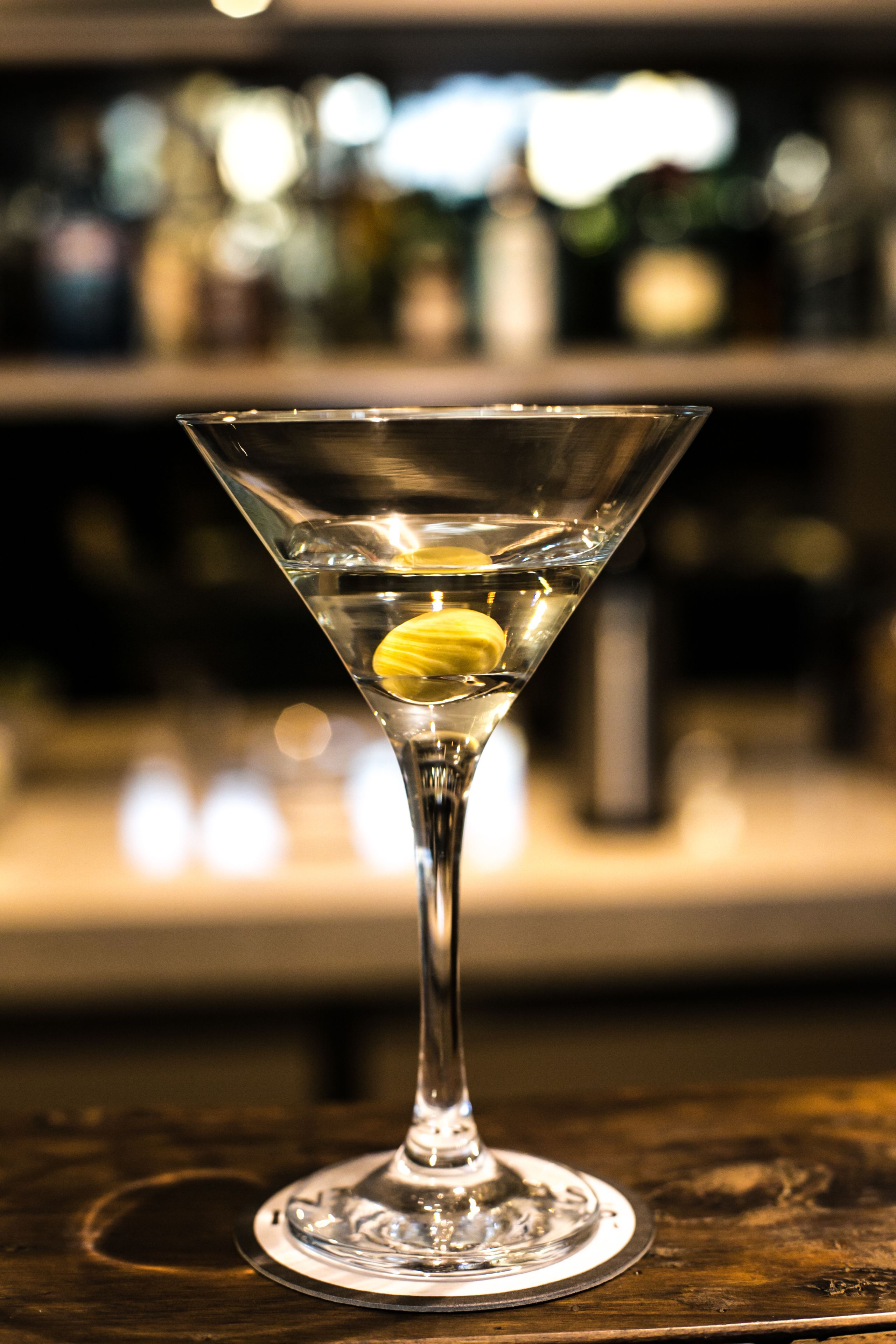 Una copa de martini con una rodaja de limón sobre una barra.