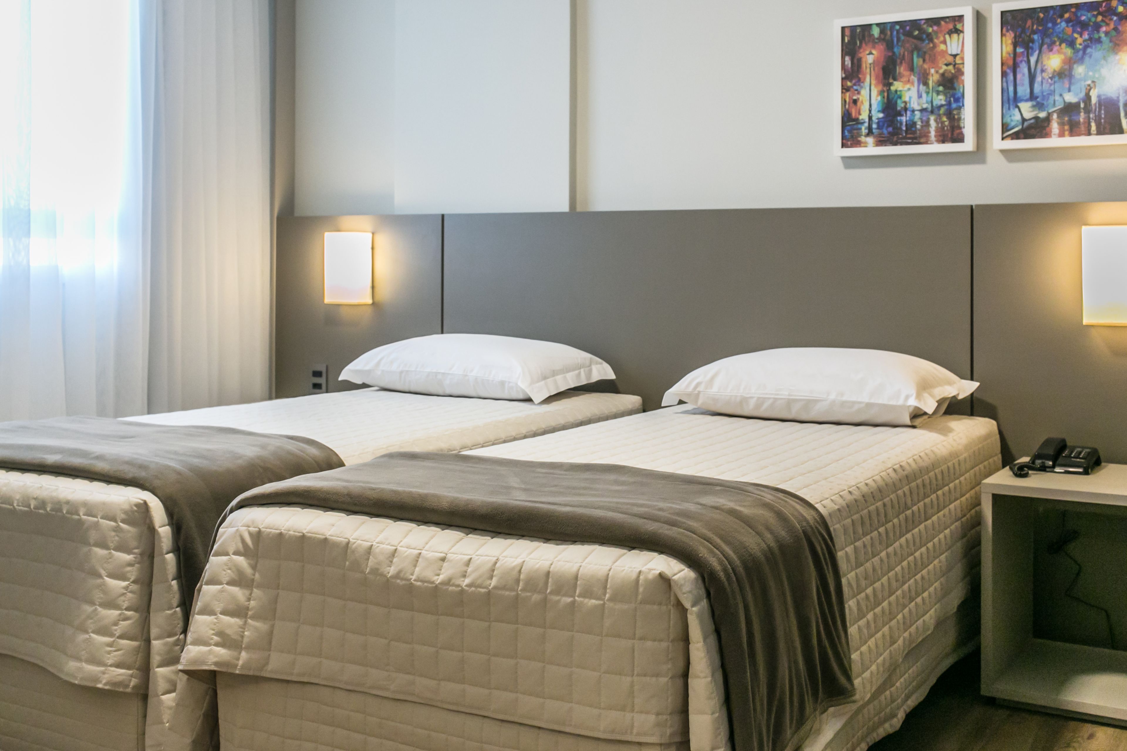 Ein Hotelzimmer mit zwei Betten, einem Nachttisch mit Telefon und einem Bild an der Wand.