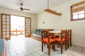 Una habitación con una mesa de comedor, sillas, un sofá, un ventilador de techo y una ventana con persianas.