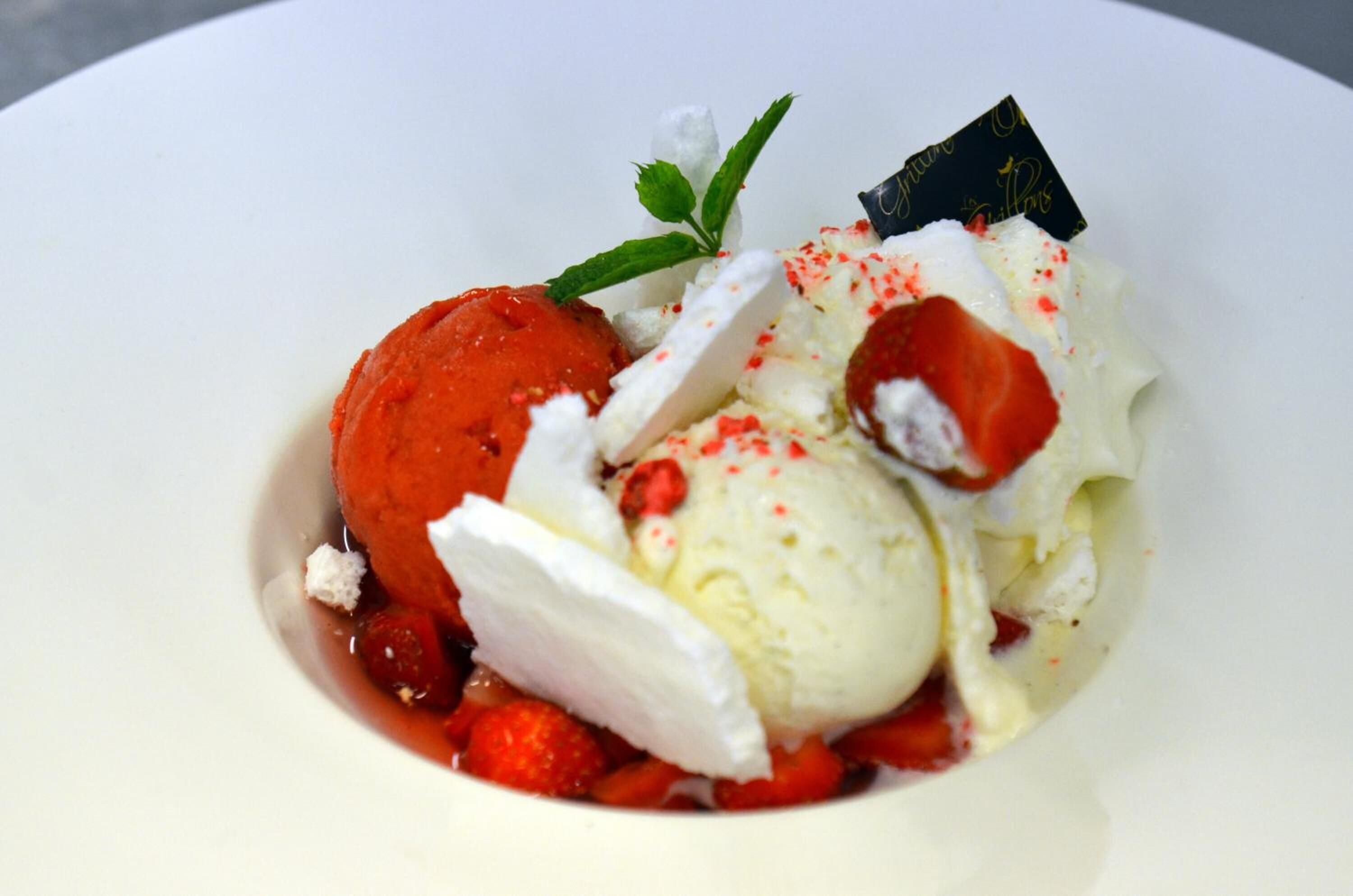 Sobremesa com sorvete e morangos em um prato branco.