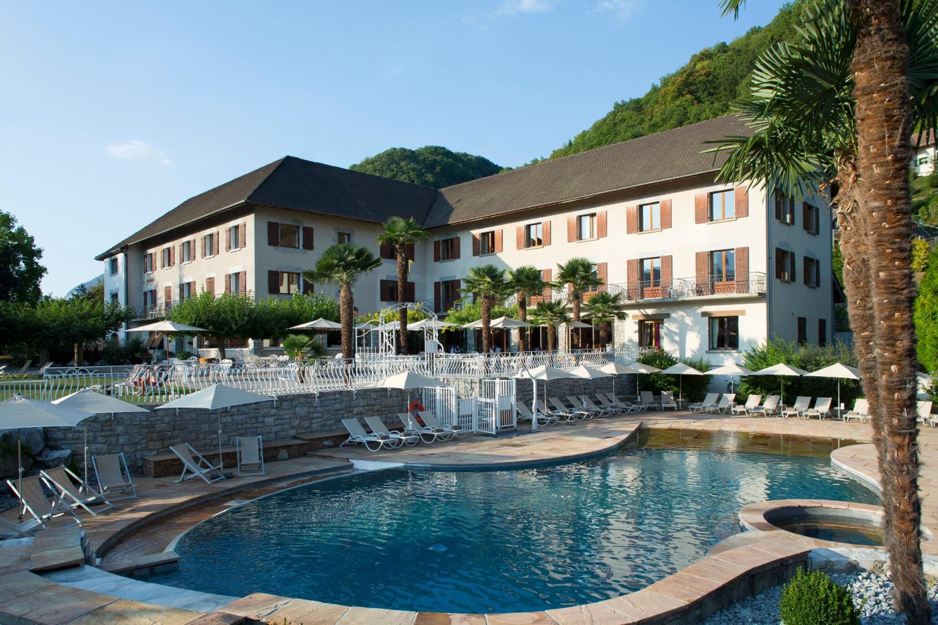 Un hotel con piscina, tumbonas y sombrillas.