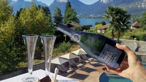 A bottle of Charles Heidsieck champagne being poured into a glass, with a bowl of fruit dessert and two empty glasses on a table. - Hôtel Les Grillons (Talloires-Montmin)