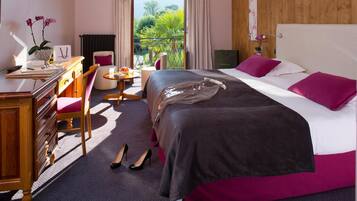 Habitación de hotel con cama, escritorio, silla, mesita y vista al exterior.