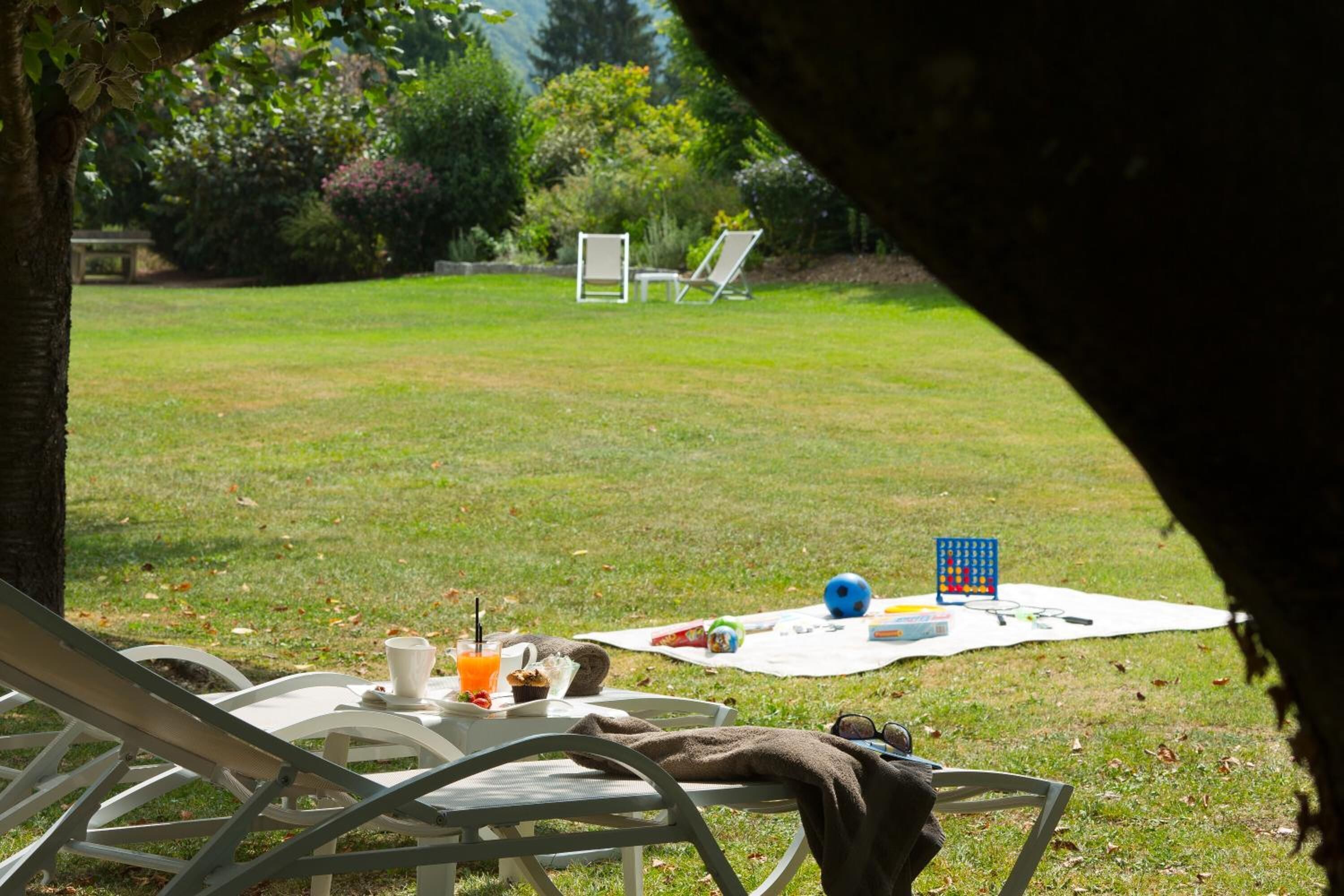 A picnic setup with a table, chairs, and a blanket on a grassy lawn.