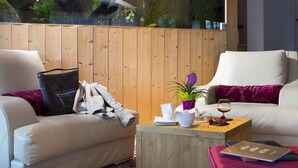 A modern living room with two sofas, a wooden coffee table, and a large aquarium. - Hôtel Les Grillons (Talloires-Montmin)