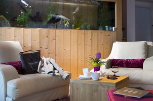 Uma sala de estar moderna com dois sofás, uma mesa de centro de madeira e um aquário grande.