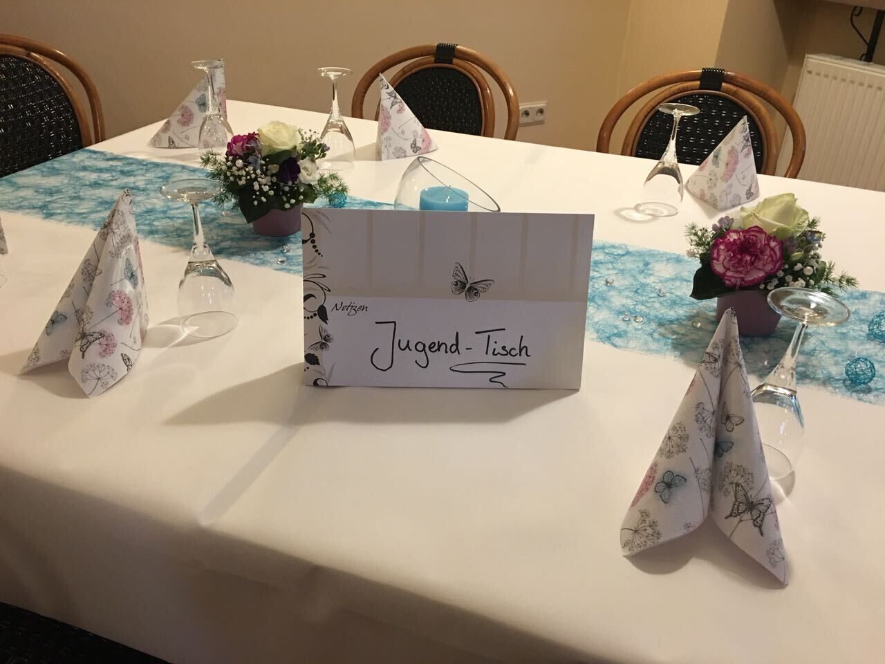 A table set with a white tablecloth, a sign reading "Jugend-Tisch," and decorative paper cones.