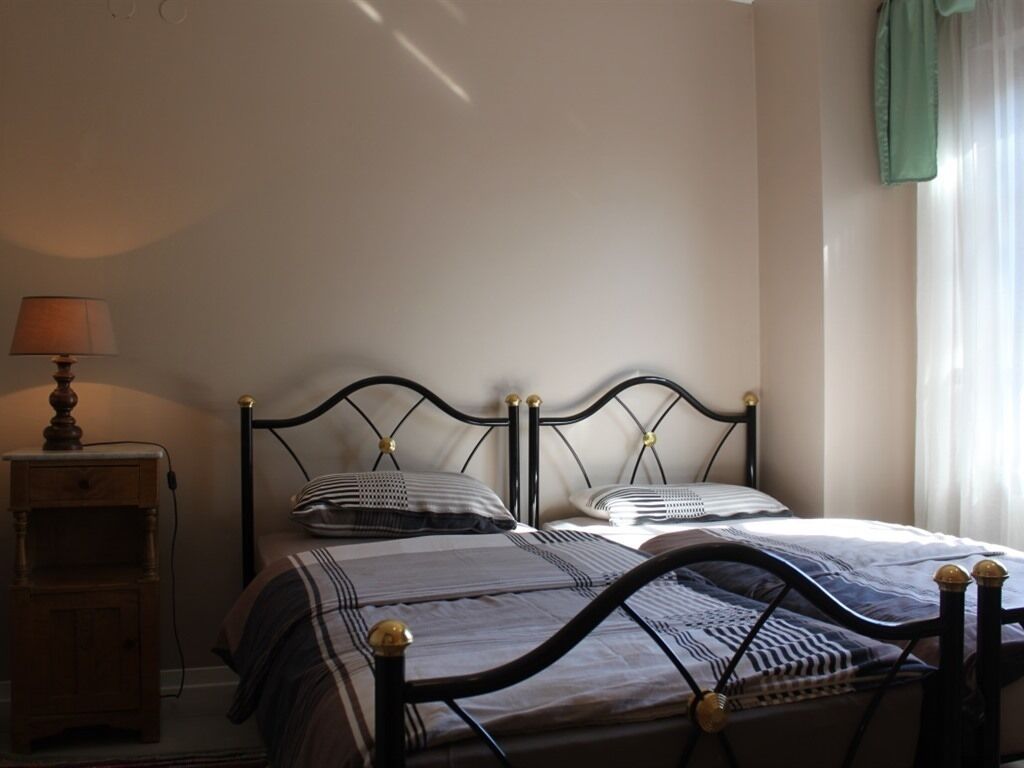 A bedroom with two beds, a nightstand, and a lamp.