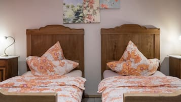 Un dormitorio doble con ropa de cama floral, cabeceros de madera y mesitas de noche con lámparas.