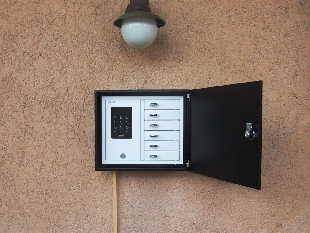 Un teclado de seguridad con cerradura en una pared beige con textura.