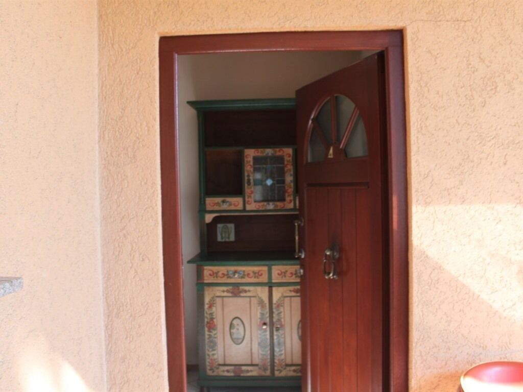 A wooden door leading to a room with a cabinet and a mirror.