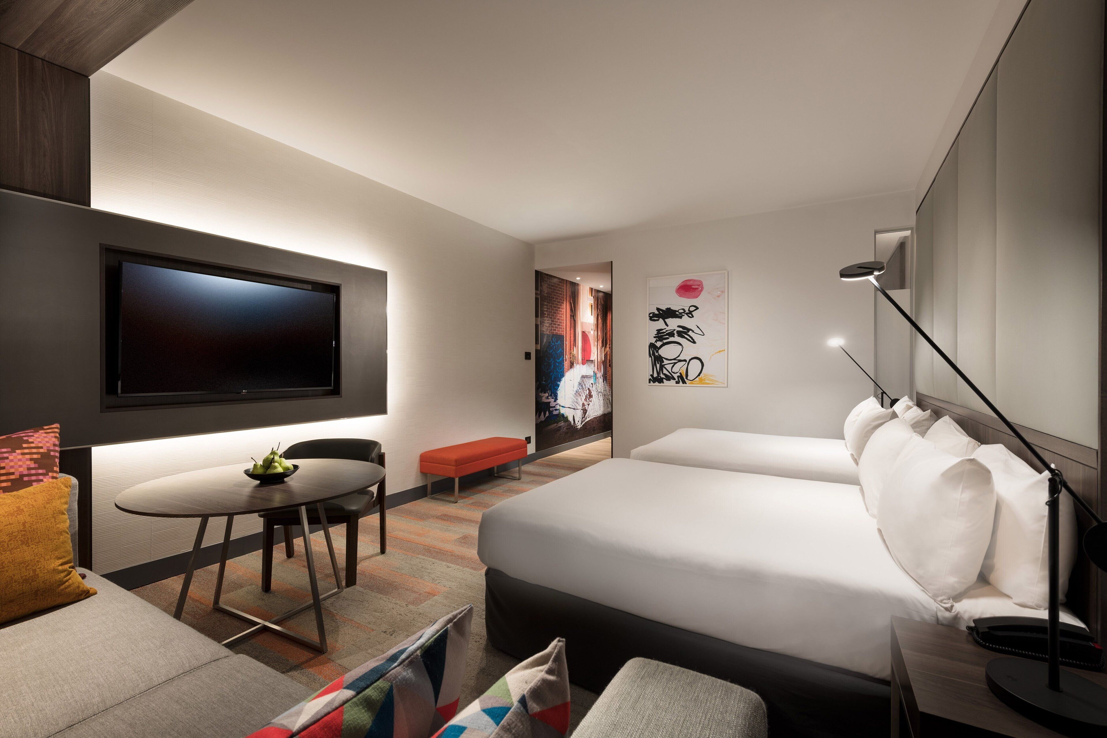 Een moderne hotelkamer met een groot bed, een bureau, een flatscreen-tv en een eethoek.