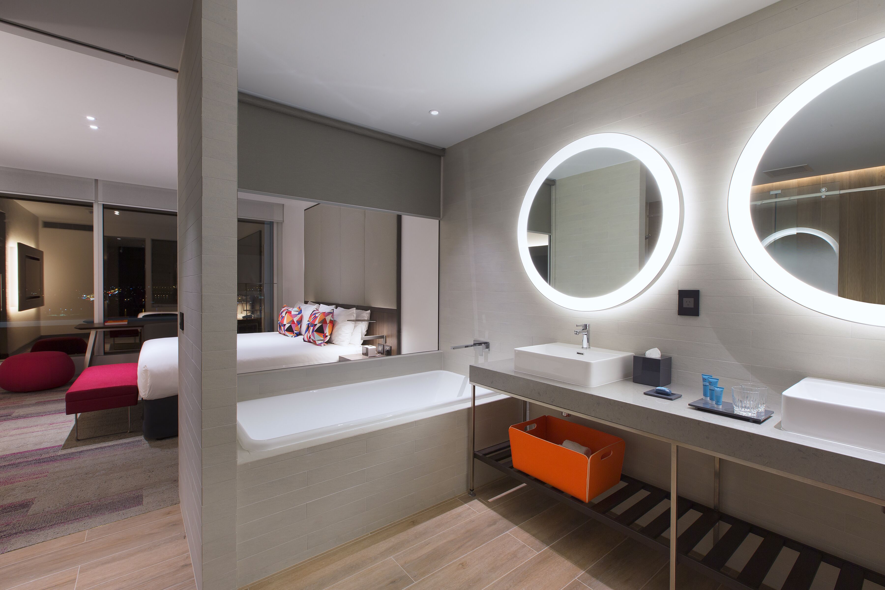 Un baño moderno con una bañera grande, dos lavamanos y dos espejos iluminados.